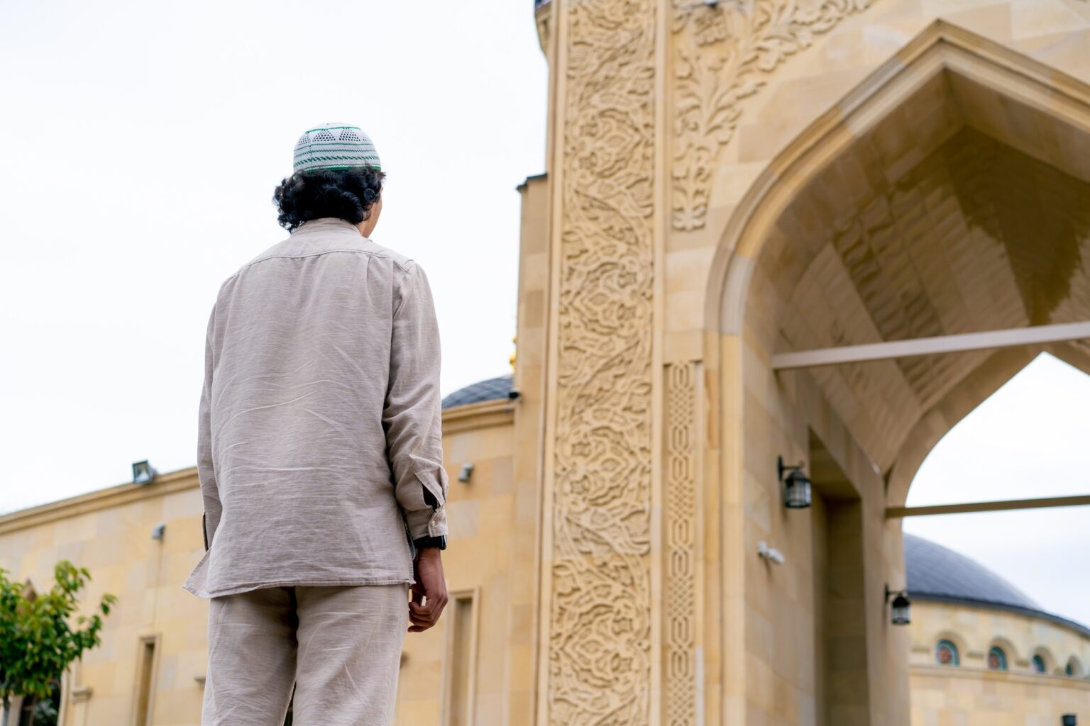 Arab man entering the inner courtyard of a mosque on a terrace with Islamic ornamentation