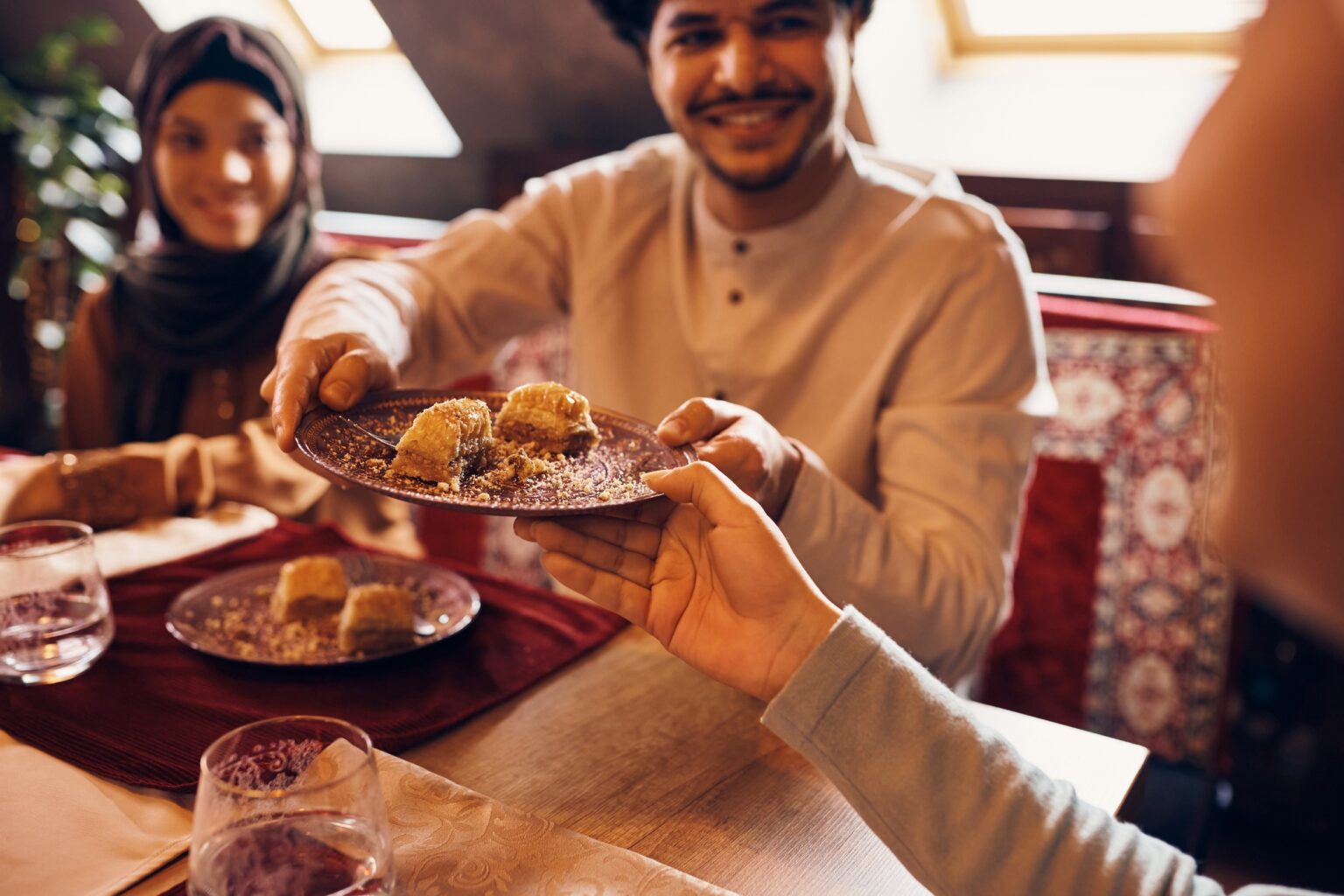 Close-up of Muslim people eating baklava for dessert at home.